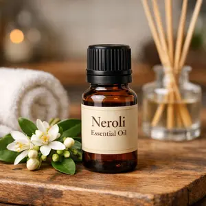 neroli essential oil bottle on wooden board and diffuser and towel in background